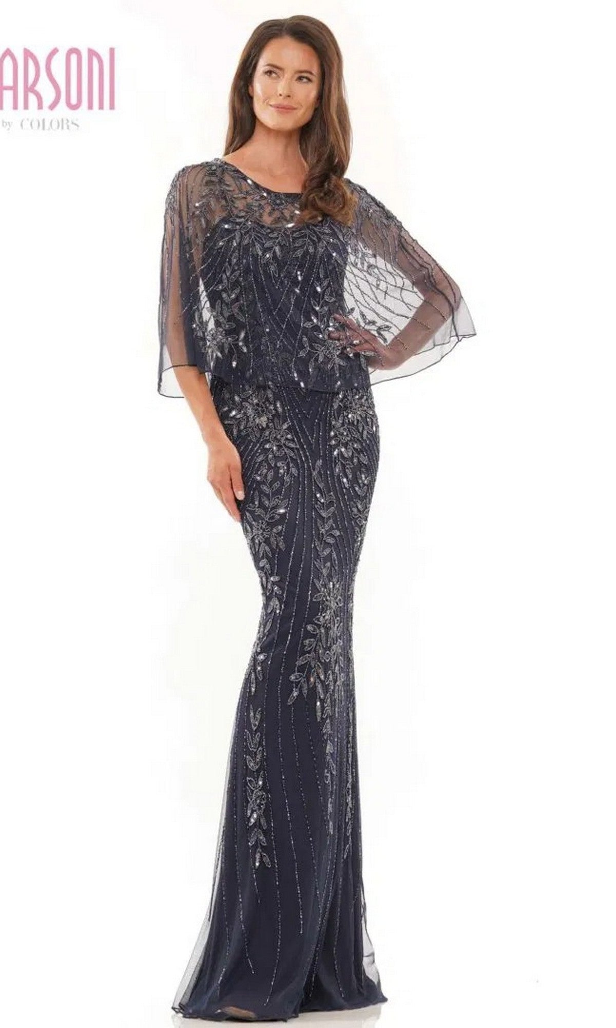 A woman wearing the Marsoni MV1201 Long Formal Dress—a navy blue, floor-length evening gown with beads and a sheer, embellished capelet—stands against a white background.